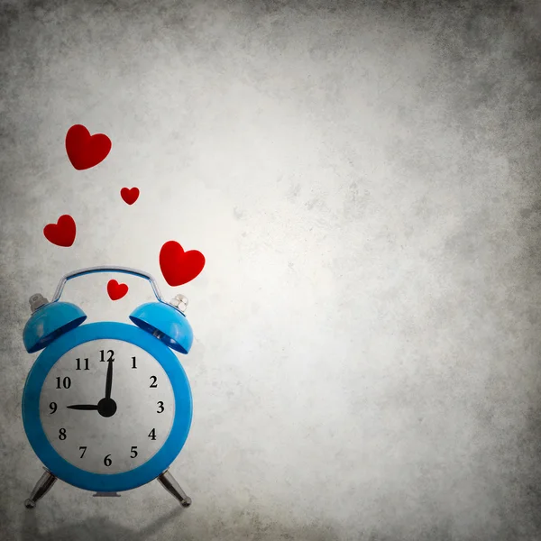 Alarm clock with floating red hearts on grunge background — Stock Photo, Image