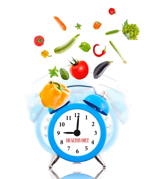 Kost koncept, väckarklockan ringer och grönsaker. — Stockfoto
