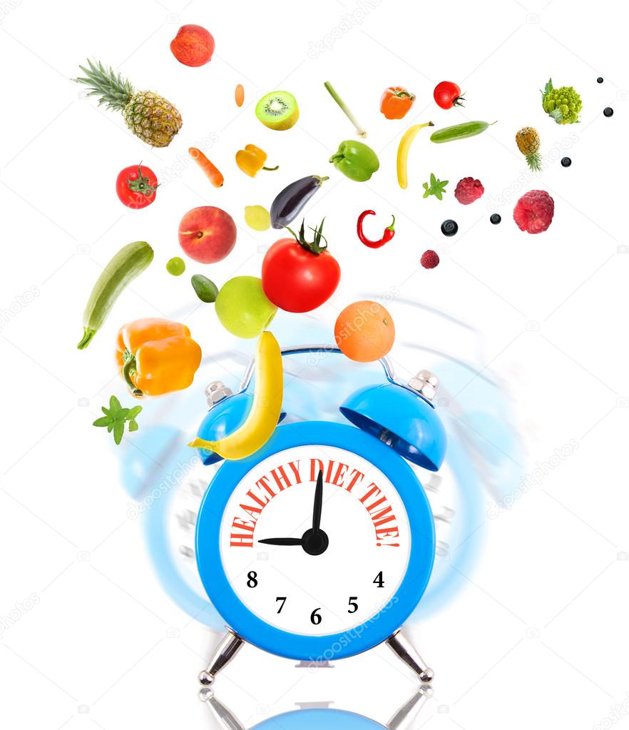 Diet concept, alarm clock ringing and fruits with vegetables.