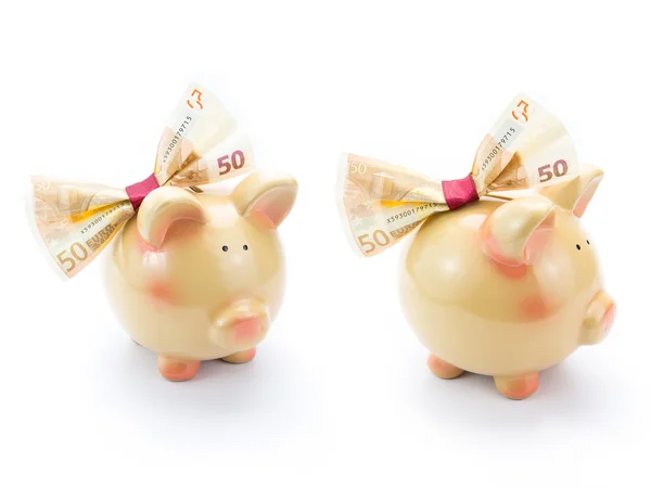 Twee schattige piggy banken met een bankbiljet boog geïsoleerd — Stockfoto