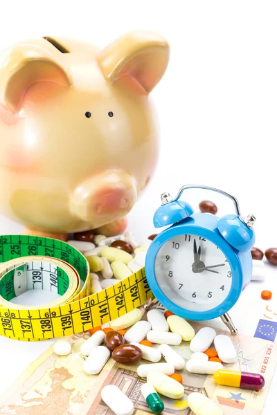 Piggy bank with pile of pills, banknotes clock and measure tape — Stock Photo, Image