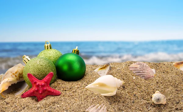 Bolas de Natal e conchas na areia com fundo do mar de verão — Fotografia de Stock