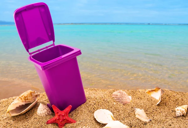 Mülleimer auf sauberem Sand und Muscheln mit Meerblick-Hintergrund — Stockfoto