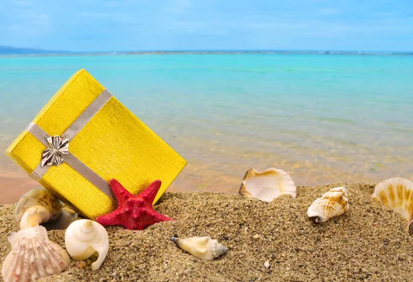 Gold-Geschenk-Box auf Sand mit Sommer Meer Hintergrund — Stockfoto