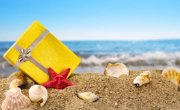 Caixa de presente de ouro na areia com fundo do mar de verão — Fotografia de Stock