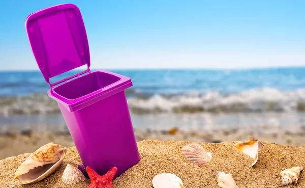 Trash can on clean sand and shells with seascape background — Stock Photo, Image