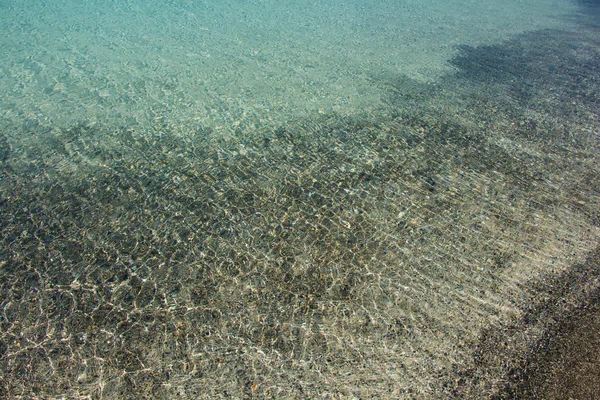 Transparante duidelijk zachte golfde water oppervlakte achtergrond — Stockfoto