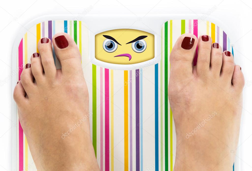 Feet on bathroom scale with angry cute face on dial