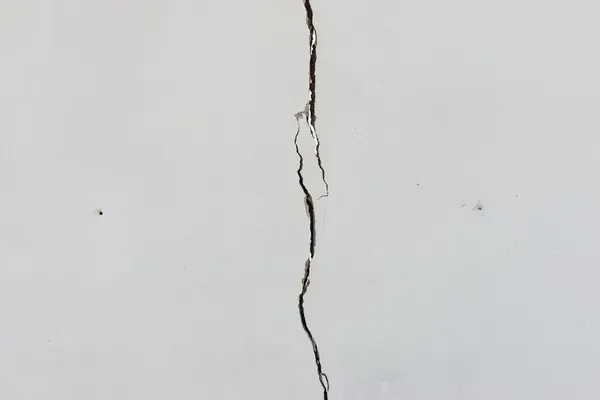 Rachaduras na parede de concreto pintada de branco sólido — Fotografia de Stock
