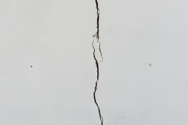 Cracks on solid white painted concrete wall