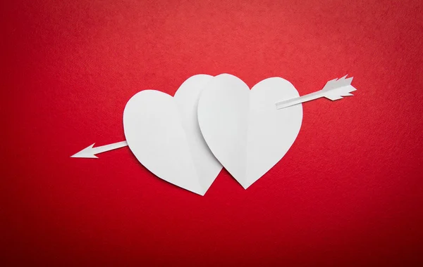 Dos corazones de papel perforados con un símbolo de flecha para el día de San Valentín —  Fotos de Stock