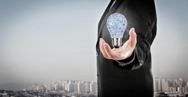 Деловой человек держит лампочку с бизнес-концепцией внутри — стоковое фото