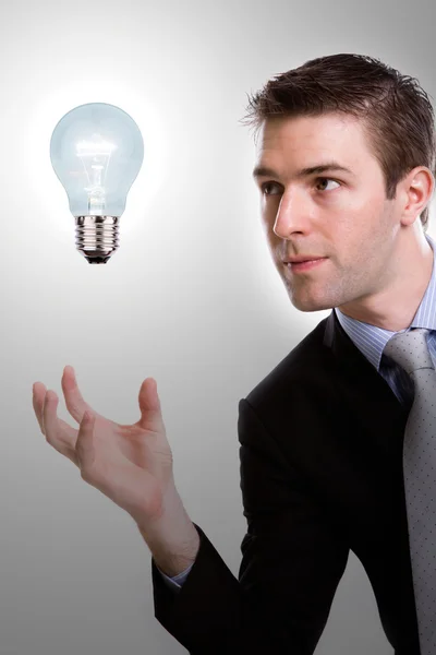 Portrait of young business man holding a light bulb — Stock Photo, Image