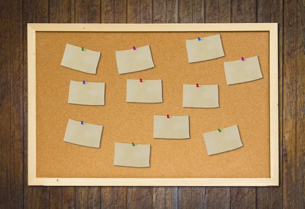 Cork bulletin board with old paper note on wood wall — Stock Photo, Image