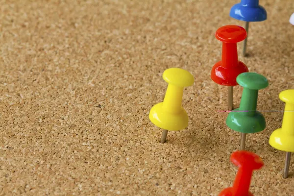 Group of colorful push pins on cork bulletin board. — Stock Photo, Image