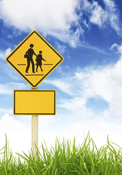 Traffic sign (School warning sign) on green grass and blue sky. — Stock Photo, Image