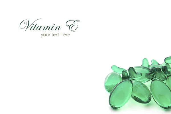 Green transparent pills of vitamin E on white background with co — Stock Photo, Image