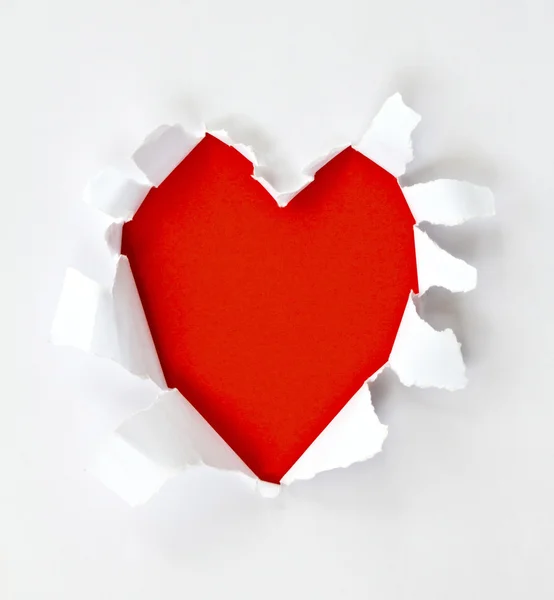 Hoja de papel con un agujero en forma de corazón contra fondo rojo brillante —  Fotos de Stock