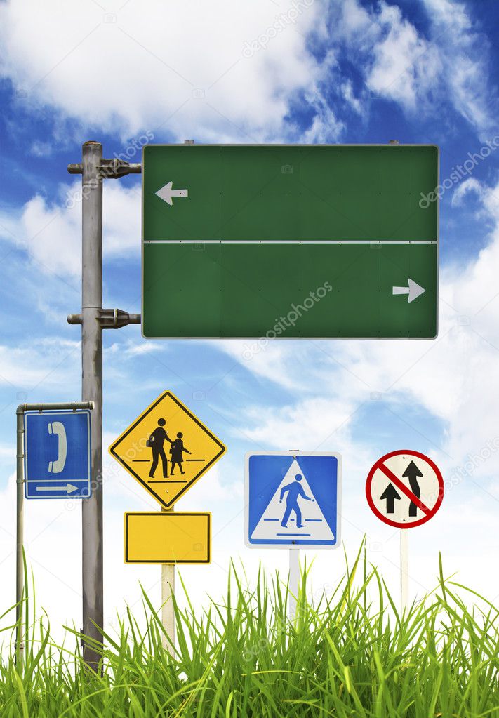 Traffic signs on green grass and blue sky.