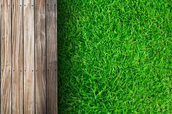 Fresca primavera erba verde con pavimento in legno — Foto Stock