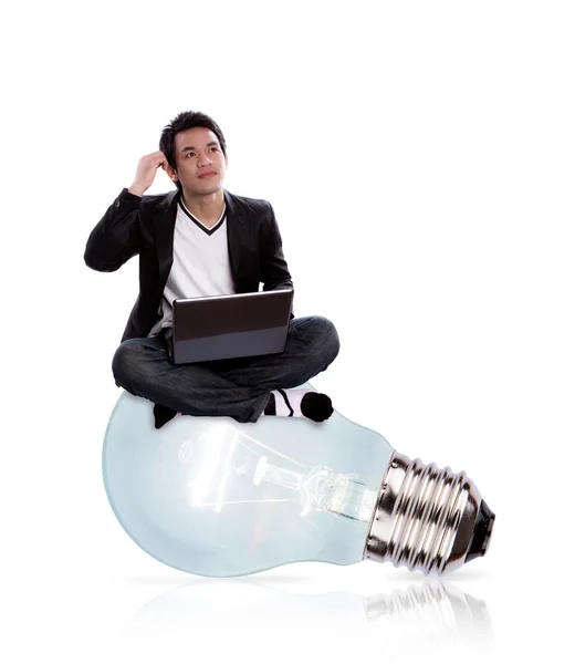 Portrait of business man using laptop sitting on a big light bu — Stock Photo, Image