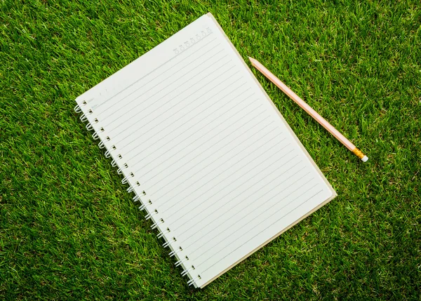 Notebook on fresh spring green grass — Stock Photo, Image