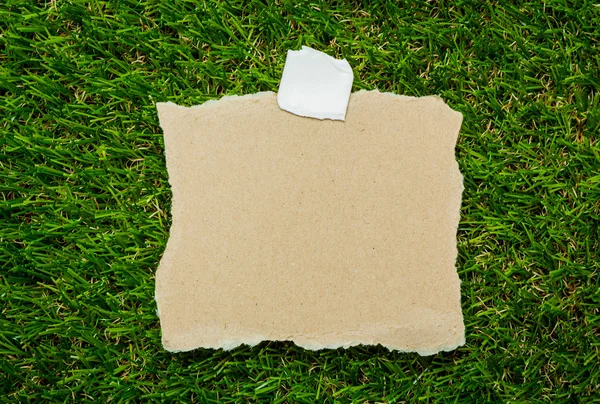 Lege gerecupereerd Opmerking papier op groen gras achtergrond — Stockfoto