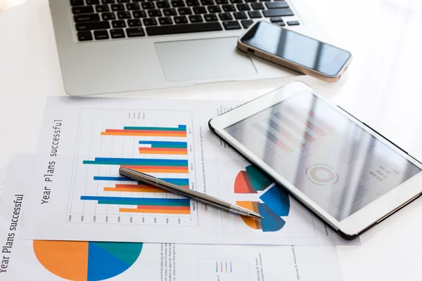 Cuadros financieros sobre la mesa con tableta y bolígrafo — Foto de Stock