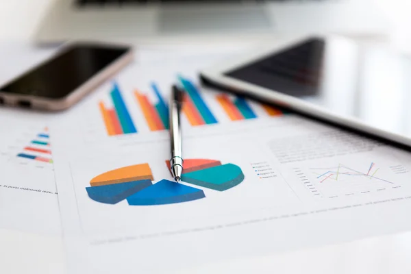 Financial charts on the table with tablet phone and pen — Stock Photo, Image