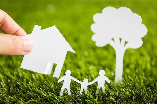 Paper cut of family with house and tree on fresh spring green gr