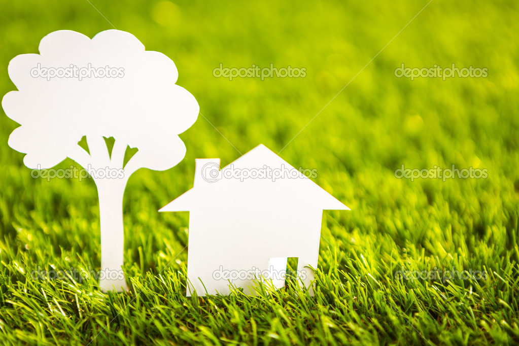 Paper cut of  house and tree on fresh spring green grass