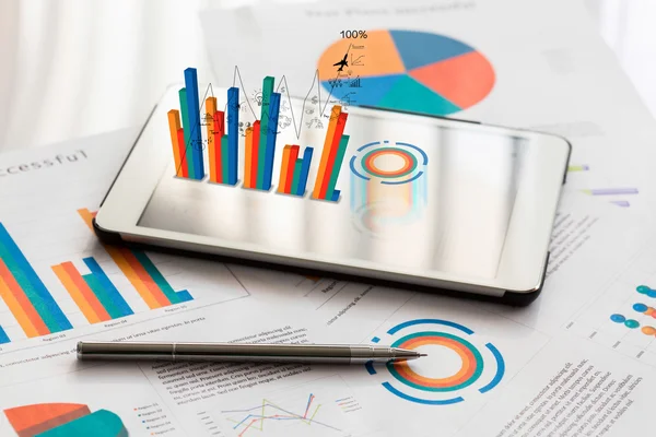 Gráficos financieros sobre la mesa con teléfono tableta y pluma — Foto de Stock