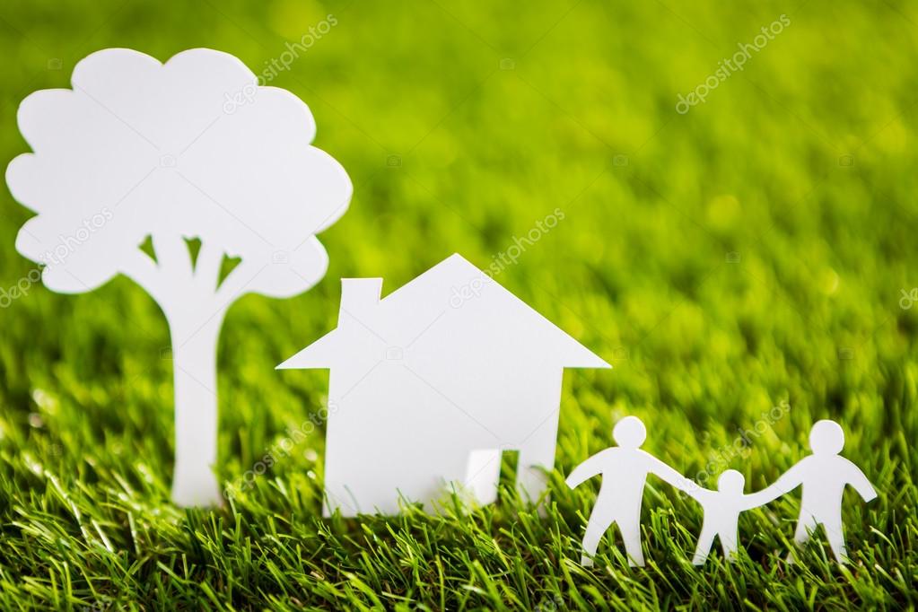 Paper cut of family with house and tree on fresh spring green gr