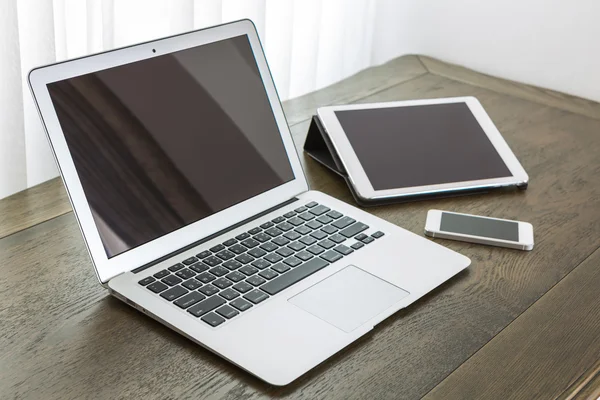 Laptop met tablet en smartphone op tafel — Stockfoto