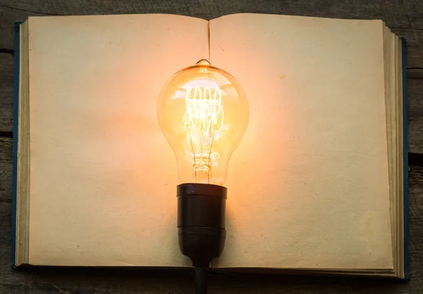 Vintage book and light bulb on wood table — Stock Photo, Image