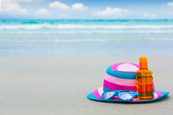 Sunscreen lotion and dark glasses with hat on the beach for summ — Stock Photo, Image