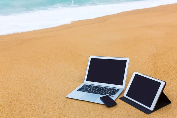 Ordenador portátil, tableta y teléfono inteligente en la playa en verano —  Fotos de Stock