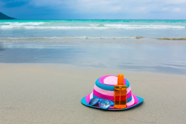 Sunscreen lotion and dark glasses with hat on the beach for summ — Stock Photo, Image