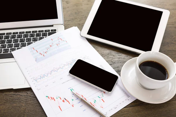 Ноутбук, планшет, смартфон и кофейная чашка с финансовой документацией — стоковое фото