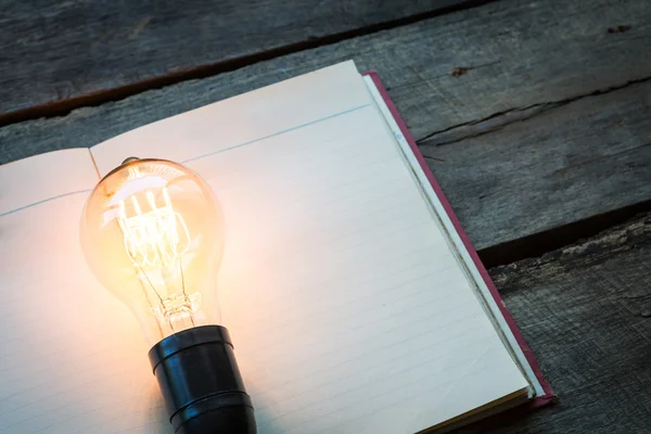 Vintage book and light bulb on wood table — Stock Photo, Image