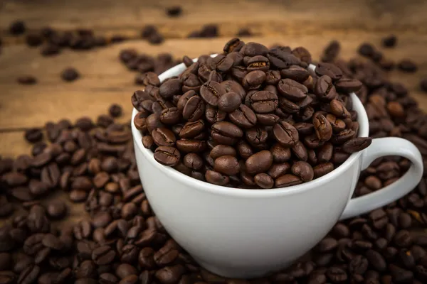 Xícara de café e grãos de café em uma mesa de madeira — Fotografia de Stock