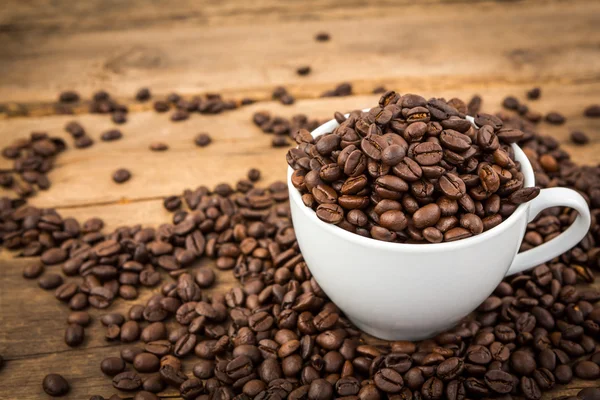 Tazza di caffè e chicchi di caffè su un tavolo di legno — Foto Stock