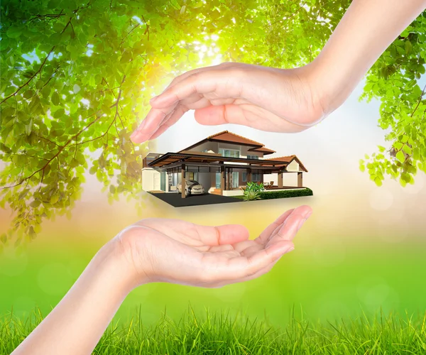 House on woman hand over Green leaf  background — Stock Photo, Image
