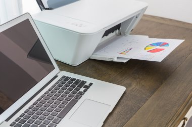 Yazıcı ve ahşap masa üstünde laptop