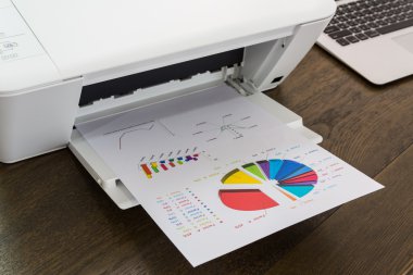Yazıcı ve ahşap masa üstünde laptop