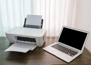 Yazıcı ve ahşap masa üstünde laptop