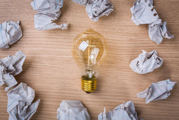 Bombilla con papel arrugado sobre fondo de madera — Foto de Stock