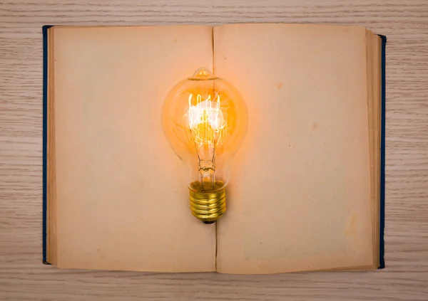 Vintage book and light bulb on wood table — Stock Photo, Image