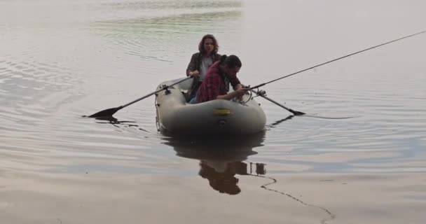 Jovens pescadores em um barco inflável no lago estão pescando. Fotografia cinematográfica. — Vídeo de Stock