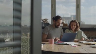 Arkadaşlar ortak bir projede birlikte çalışıyorlar, gülümsüyorlar ve gülüyorlar..